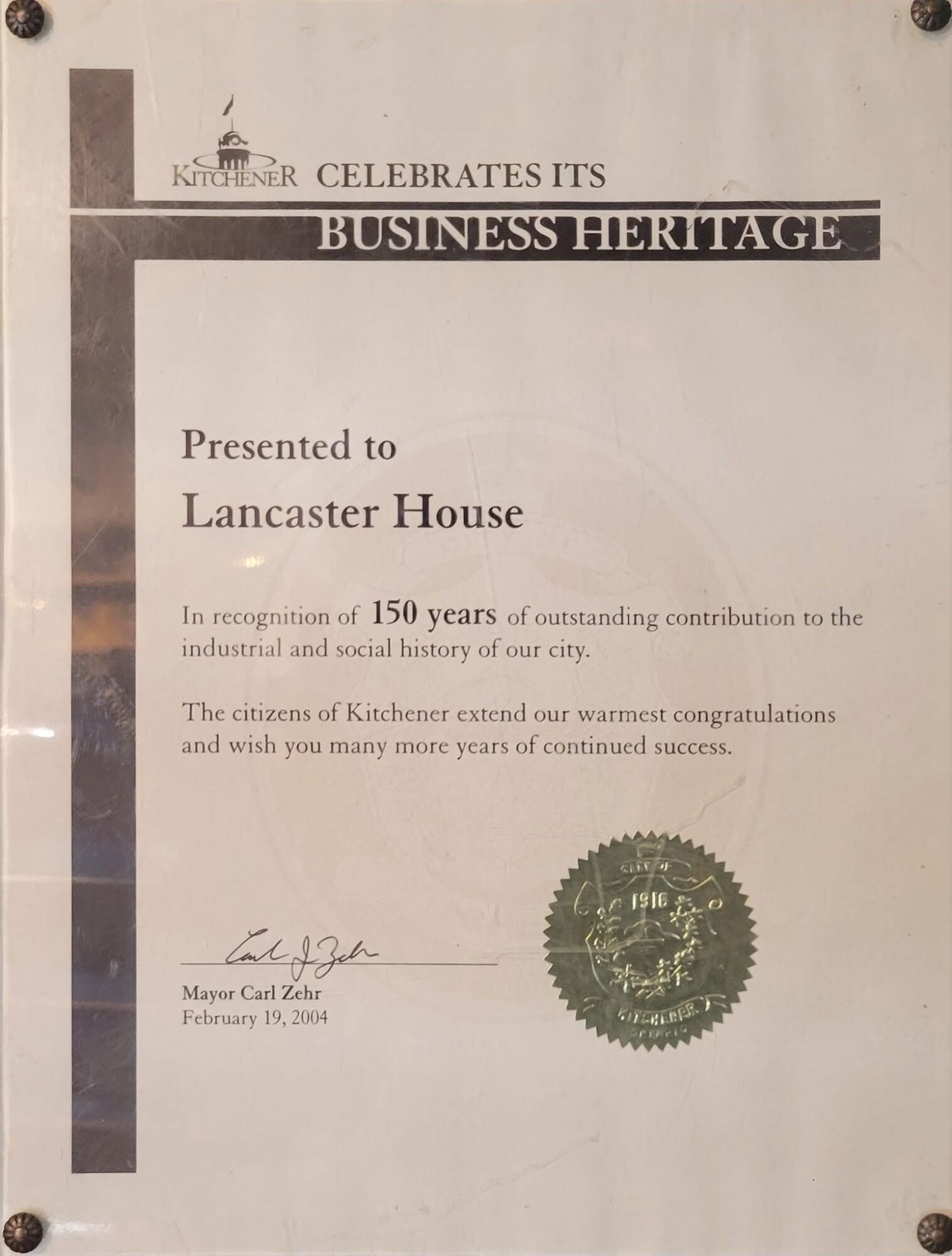A framed City of Kitchener heritage certificate presented to Lancaster House in 2004, recognizing 150 years of contribution to the city’s industrial and social history; this original print hangs inside The Lancaster Smokehouse as part of its historical display.